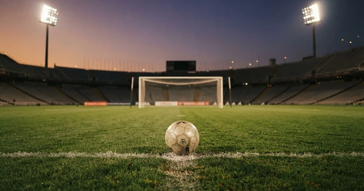 Ein Fußball liegt im Strafraum direkt vor dem Tor mit Netz, im Hintergrund leere Ränge bei Dämmerung.