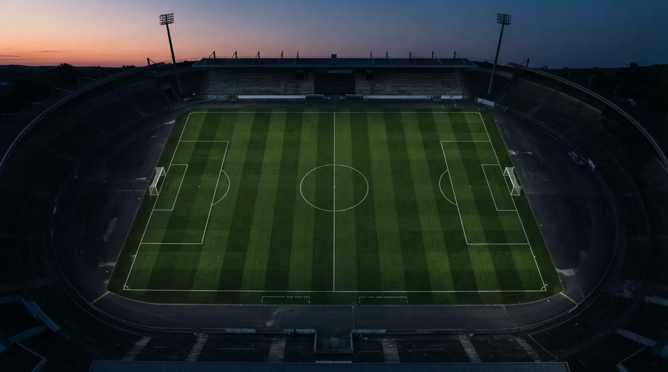Ein Fußballplatz am Abend aus der Vogelperspektive, Flutlichtmasten ausgeschaltet, die Rasenlinien deutlich sichtbar.