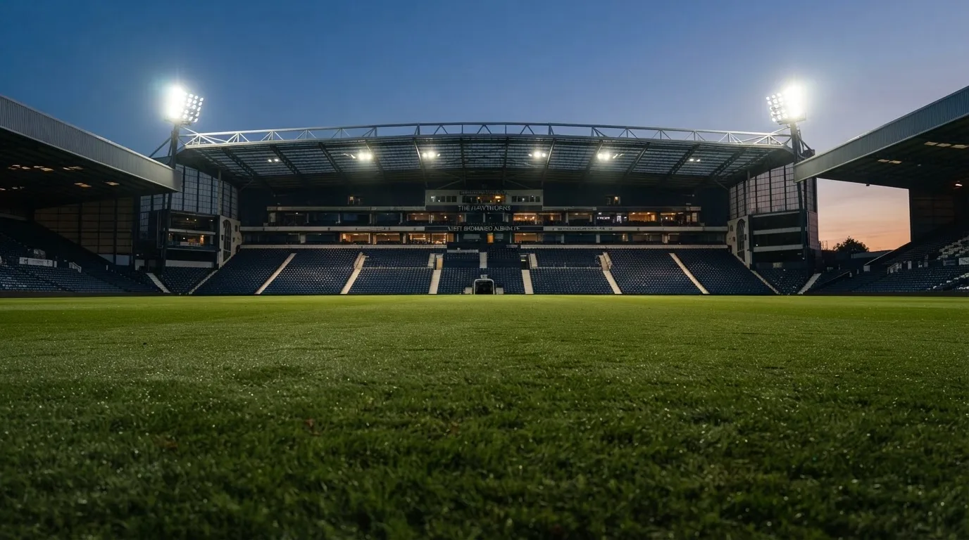 Ein Stadion unter Flutlicht aus der Ferne, davor ein stilles Feld im Dämmerlicht.