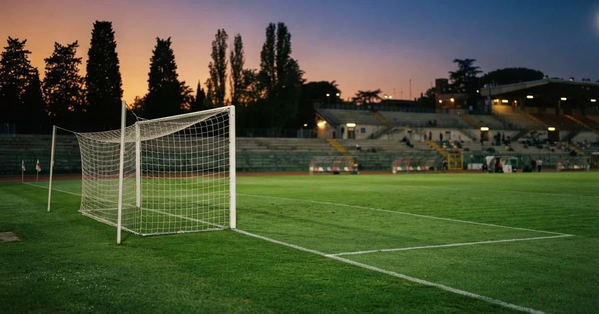 Ein Fußballtor mit Netz auf einem leeren Platz im Abendlicht, der Rasen frisch gemäht, im Hintergrund Zypressen.